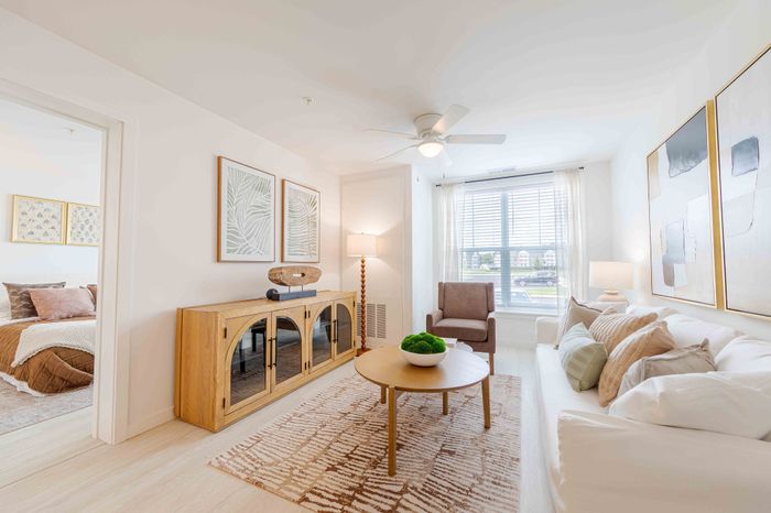 Bright and inviting living room with contemporary decor, featuring plush seating, a stylish wooden sideboard, and large windows offering natural light.