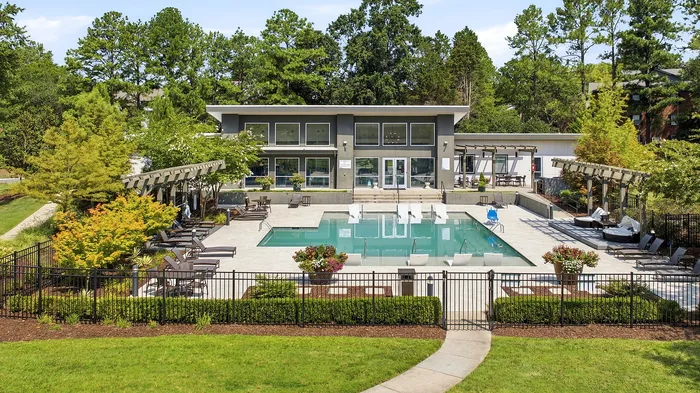 Contemporary apartment complex with luxury poolside amenities, surrounded by lush greenery and stylish outdoor seating.