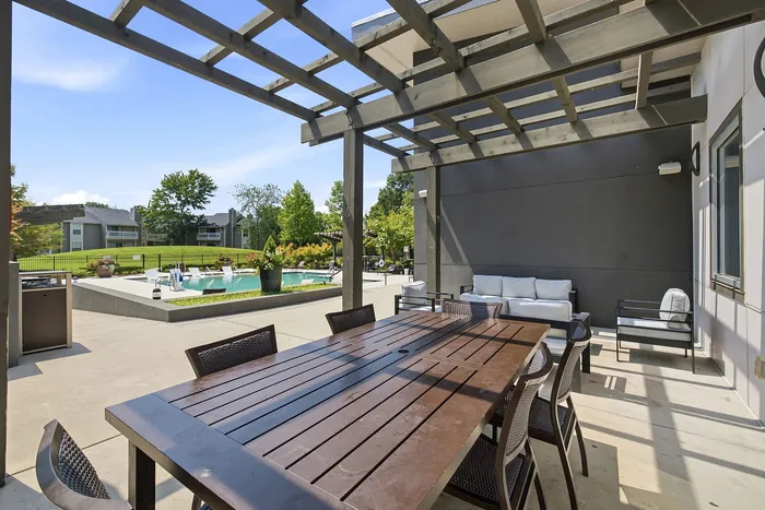 Elegant outdoor patio with stylish pergola overlooking a pristine pool and lush green landscape.