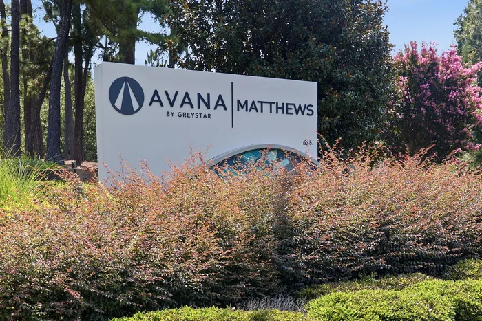 Welcome to Avana Matthews by Greystar, a serene community entrance surrounded by lush greenery and vibrant landscaping.
