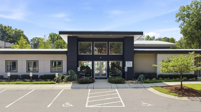 Modern apartment complex entrance with sleek design, lush landscaping, and accessible parking.