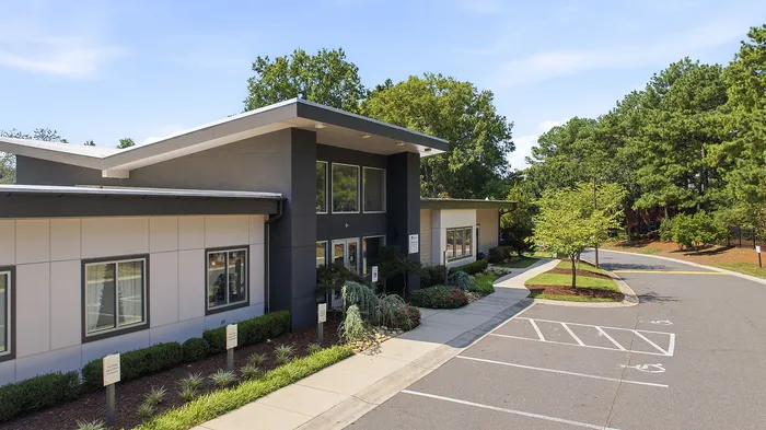 Modern building with sleek architecture surrounded by lush greenery and a tranquil pathway, showcasing an inviting entrance.