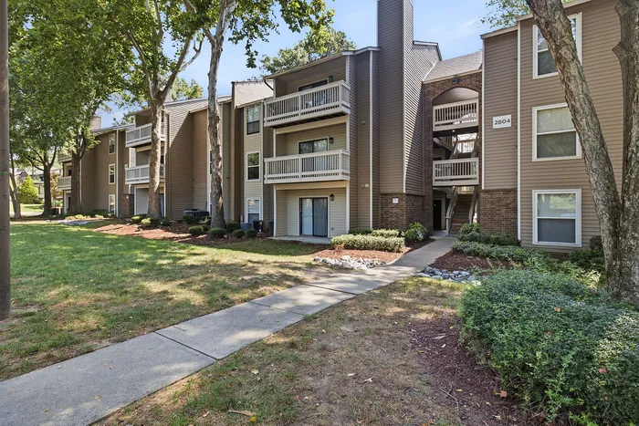 Contemporary apartment complex with charming balconies, lush greenery, and a peaceful pathway.