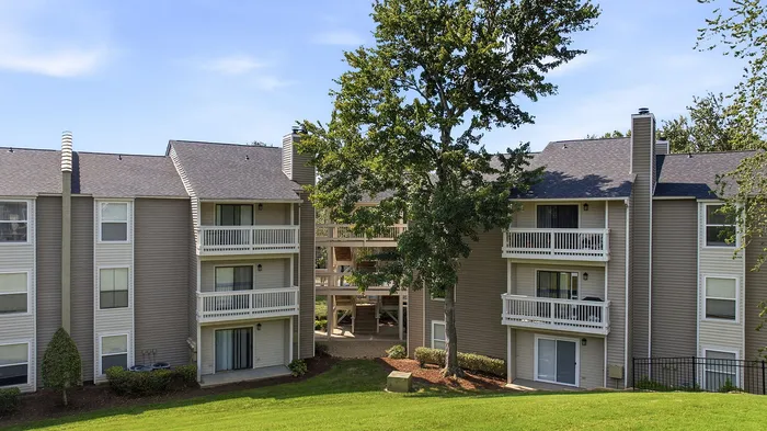 Charming apartment complex with modern siding, private balconies, and lush green landscaping, perfect for comfortable living.