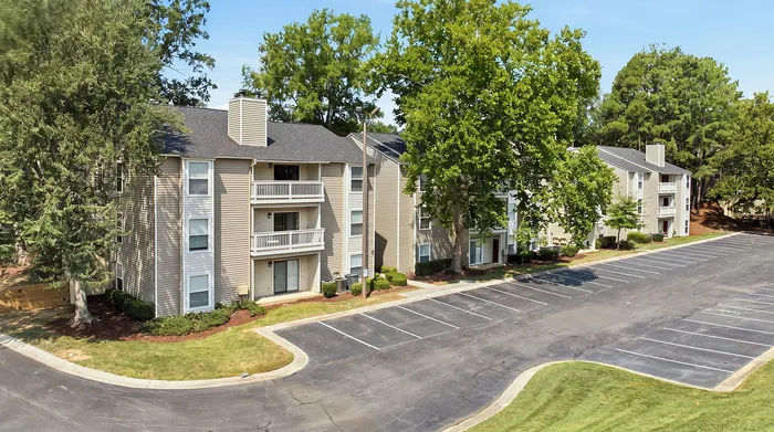 Charming apartment complex surrounded by lush greenery with ample parking and inviting balconies.