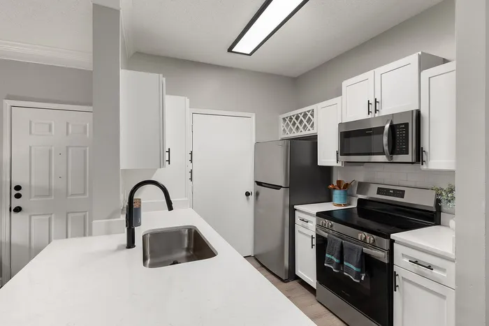 Modern kitchen with sleek appliances, stylish white cabinets, and a spacious countertop, perfect for entertaining.