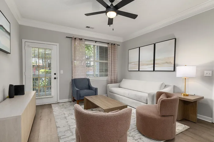 Chic living room with modern decor, featuring a cozy white sofa, stylish armchairs, and large windows for natural light.