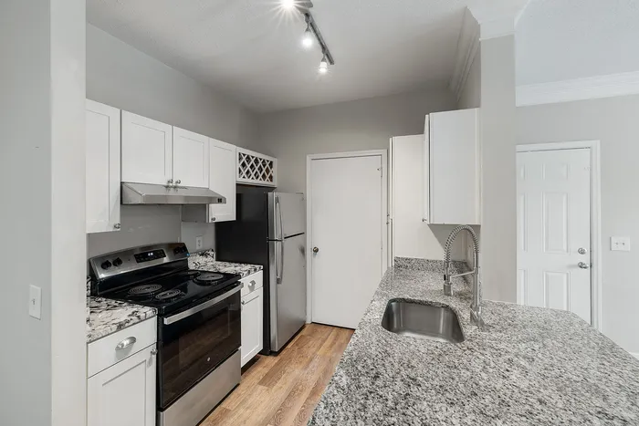 Modern kitchen with sleek granite countertops, stainless steel appliances, and elegant white cabinetry.