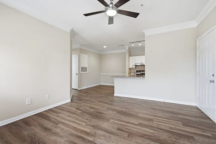 Modern open-plan living space with elegant hardwood floors, stylish ceiling fan, and a sleek kitchen featuring granite countertops.