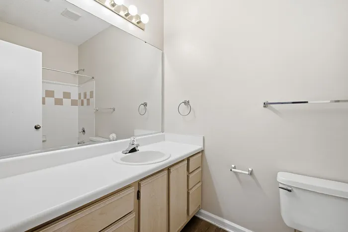 Modern bathroom with a sleek white countertop, spacious mirror, and a stylish bathtub with elegant tile design.