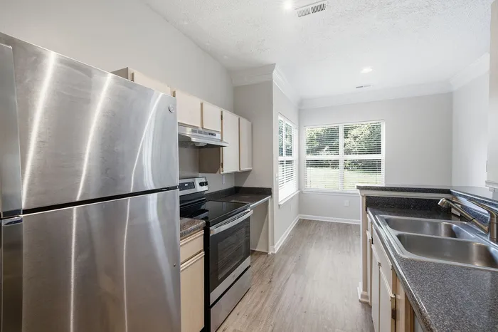 Bright and modern kitchen featuring sleek stainless steel appliances, elegant countertops, and abundant natural light through large windows.