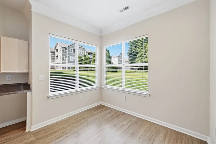 Bright corner space with large windows overlooking a lush green exterior, creating a serene atmosphere.