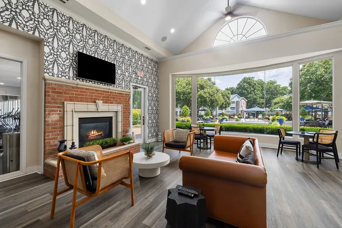 Inviting communal living space with a cozy fireplace, modern seating, and expansive windows offering scenic views of lush greenery.