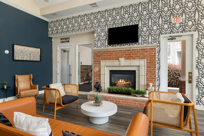Inviting lounge area with elegant decor, featuring cozy brick fireplace, chic seating, and access to the fitness center.