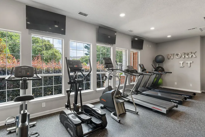 Bright and modern fitness center with state-of-the-art equipment, large windows, and motivational 'WORK IT' decor.