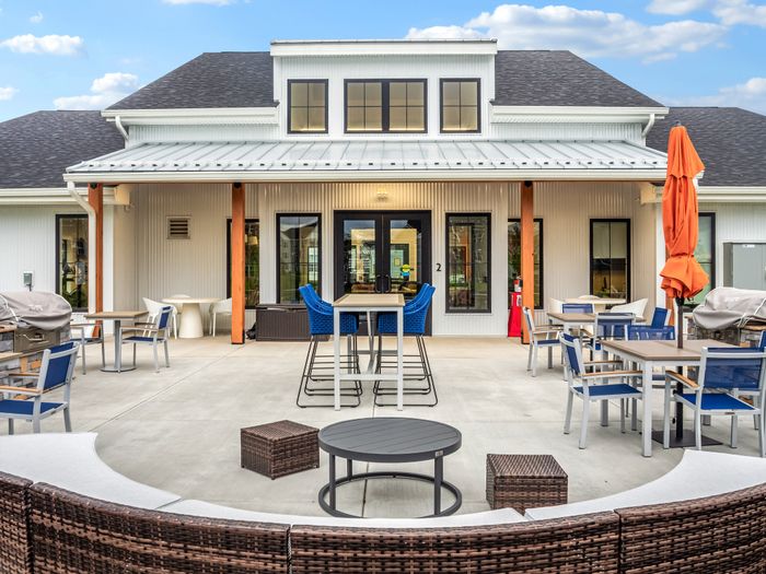 Charming outdoor patio area with contemporary seating, stylish tables, and vibrant umbrellas under a clear sky, perfect for relaxation and social gatherings.