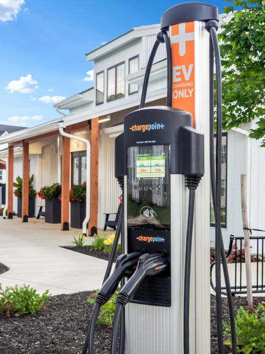 Modern EV charging station set against a stylish apartment complex with lush landscaping, showcasing eco-friendly living.