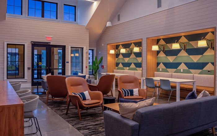Chic and modern lounge area with stylish leather chairs, geometric wall designs, and ambient lighting for a cozy atmosphere.