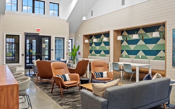 Inviting modern lounge area with stylish tan chairs, geometric wall designs, and cozy seating alcoves, perfect for relaxation and socializing.