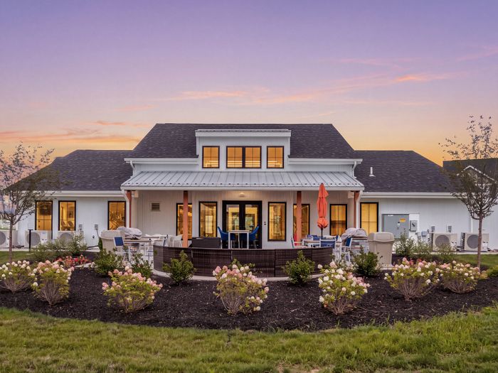 Charming suburban home with elegant patio seating, surrounded by lush landscaping and vibrant flowers at sunset.