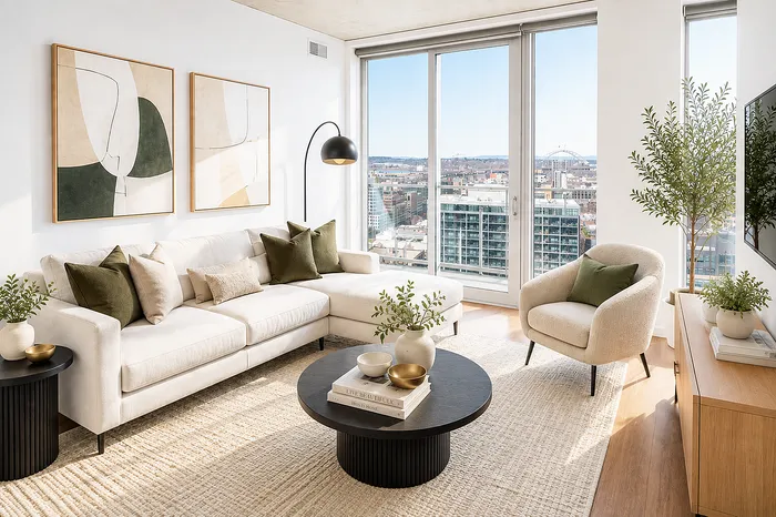 Chic urban living room with panoramic city views, featuring a modern cream sofa, stylish artwork, and abundant natural light through floor-to-ceiling windows.