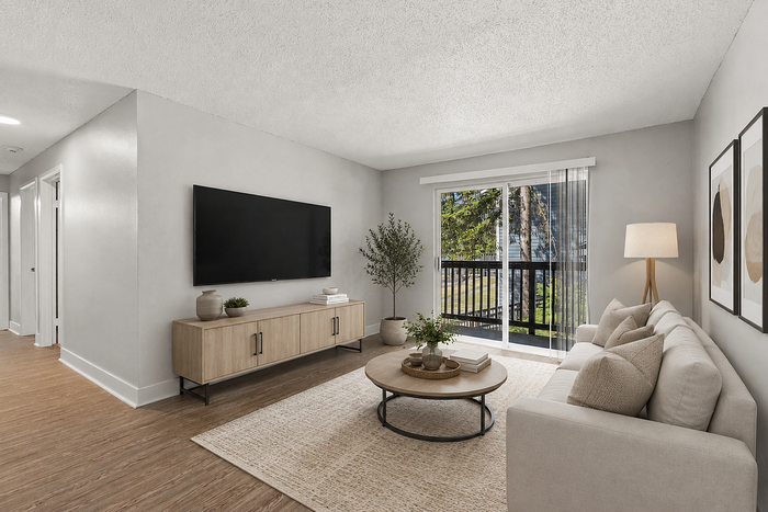 Inviting living room with modern decor, plush sofa, sleek TV setup, and abundant natural light from a sliding glass door opening to a charming balcony.