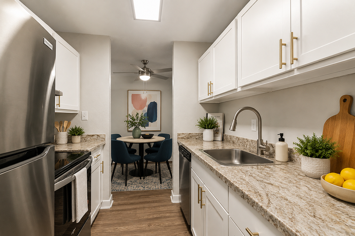 Elegant kitchen with sleek stainless steel appliances, white cabinetry, and granite countertops leading to a cozy dining area with stylish decor and modern lighting.