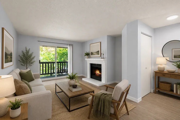 Inviting living room with a cozy fireplace, plush seating, and a view of lush greenery through large glass doors.