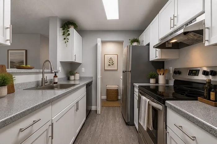 Modern kitchen with sleek white cabinetry, stainless steel appliances, and elegant countertops, accented by lush greenery.