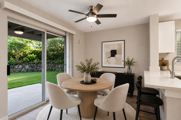Chic dining area in modern apartment with elegant furniture, large sliding glass doors to lush greenery, and contemporary light fixture.