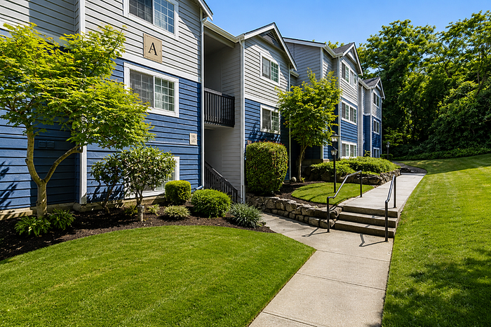 Charming apartment exterior with vibrant blue siding and well-maintained landscaping, nestled in a lush green neighborhood.