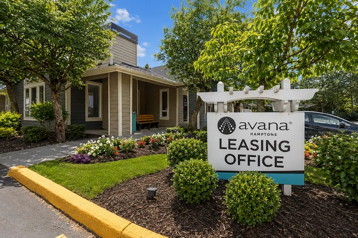 Charming leasing office at Avana Hamptons, surrounded by lush greenery and vibrant flowers, with a welcoming exterior and inviting atmosphere.
