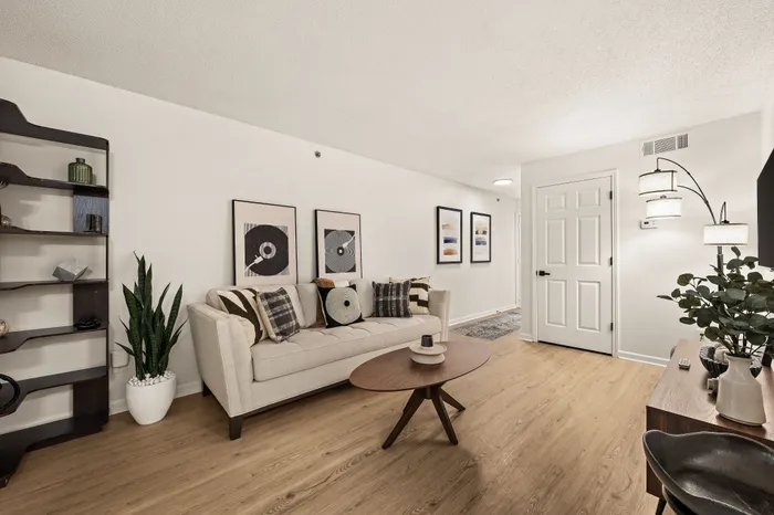 Cozy living room with modern decor, featuring a plush sofa, sleek coffee table, and stylish wall art, complemented by warm wooden flooring and soft lighting.