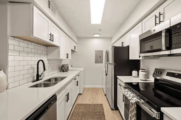 Modern kitchen with sleek stainless steel appliances, elegant white cabinetry, and a stylish subway tile backsplash.