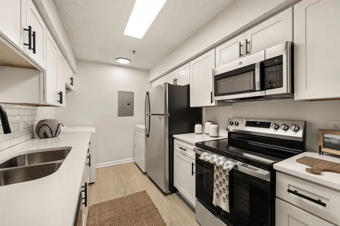 Modern kitchen with sleek white cabinetry, stainless steel appliances, and elegant tile backsplash.