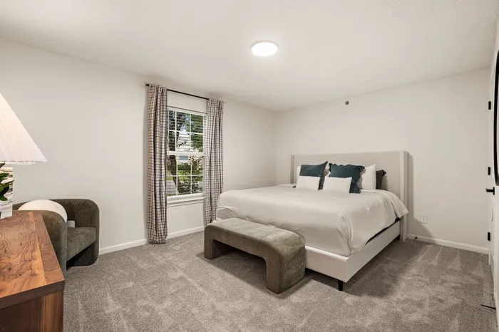 Inviting bedroom furnished with a plush bed, elegant decor, and cozy carpeting, offering a serene atmosphere.