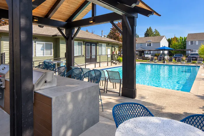 Inviting poolside oasis featuring stylish outdoor seating and a modern BBQ area under a charming pergola.