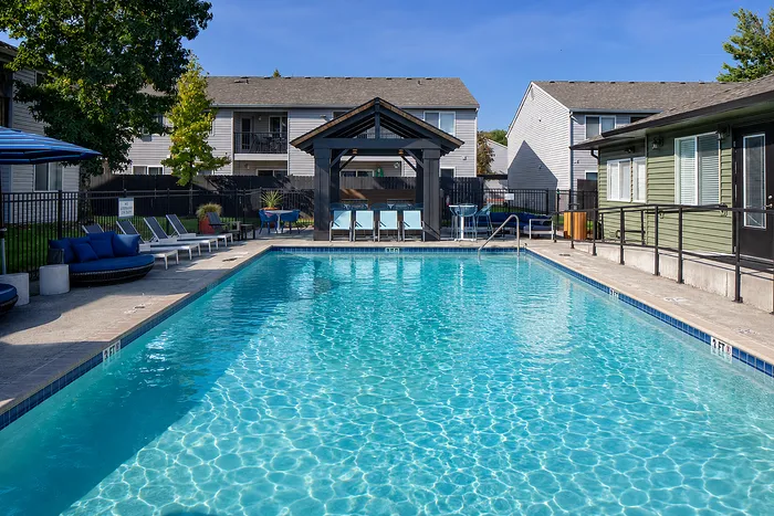 Inviting outdoor pool area with modern lounge chairs, shaded seating, and vibrant community atmosphere.