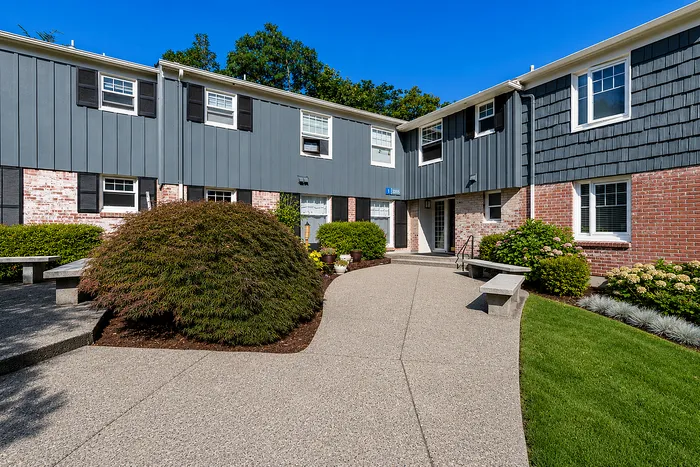 Charming apartment exterior with modern facade, lush landscaping, and inviting walkway.
