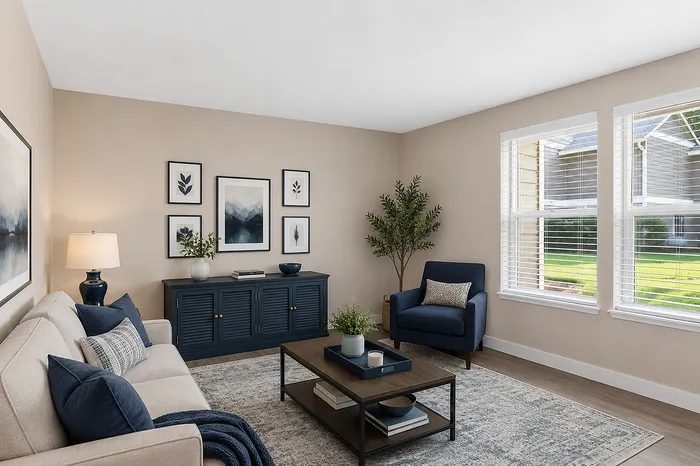 Inviting living room with elegant decor, featuring a comfortable sofa, stylish armchair, and large windows offering natural light.
