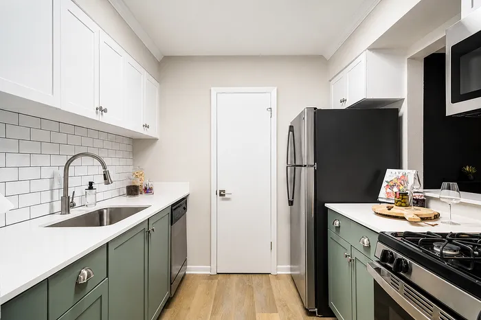 Contemporary kitchen with elegant white cabinets, modern stainless steel appliances, and charming subway tile backsplash.