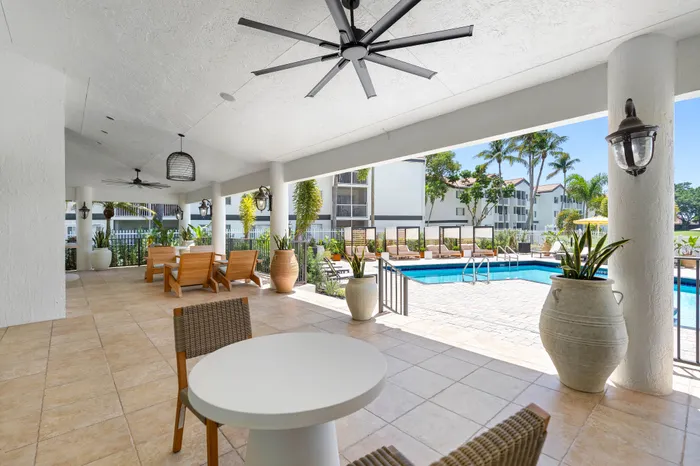 Inviting outdoor lounge with elegant furniture overlooking a pristine swimming pool, surrounded by lush tropical greenery.