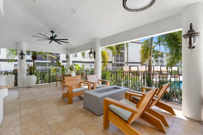Inviting outdoor patio space featuring modern wooden seating, elegant planters, and a view of lush tropical greenery.