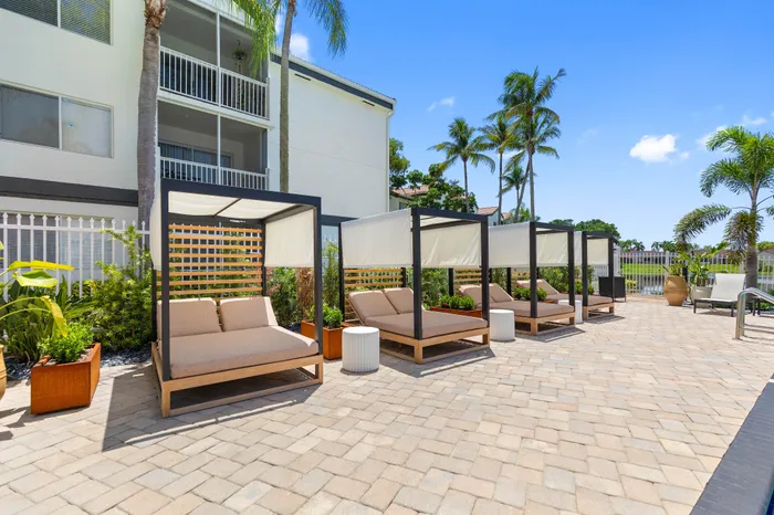 Luxurious outdoor lounge area with chic cabana-style seating, surrounded by lush greenery and swaying palm trees.