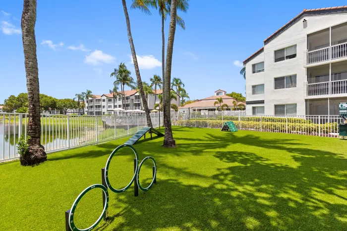 Charming apartment complex with lush green lawns, towering palm trees, and a serene pond view.
