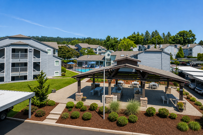 Vibrant apartment complex with charming outdoor pavilion, lush landscaping, and glistening pool, ideal for relaxed living.