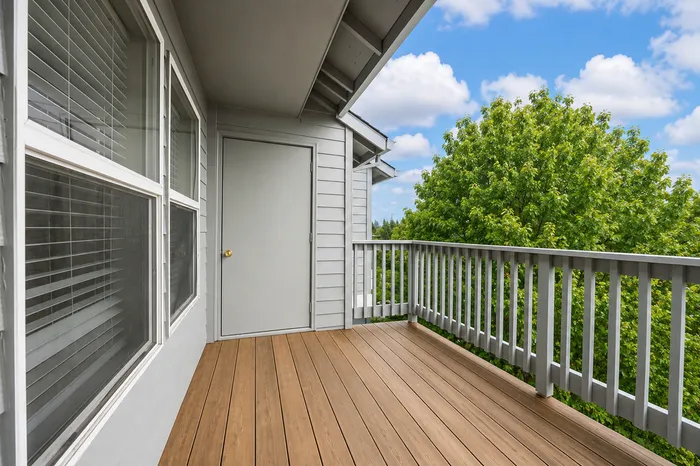 Charming balcony with wood decking and lush tree view, perfect for relaxation and outdoor enjoyment.