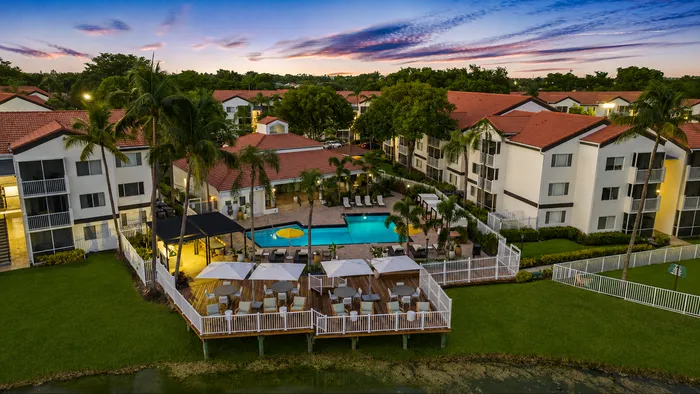 Inviting apartment community with a serene pool area, surrounded by lush landscaping and elegant buildings, ideal for tranquil living.