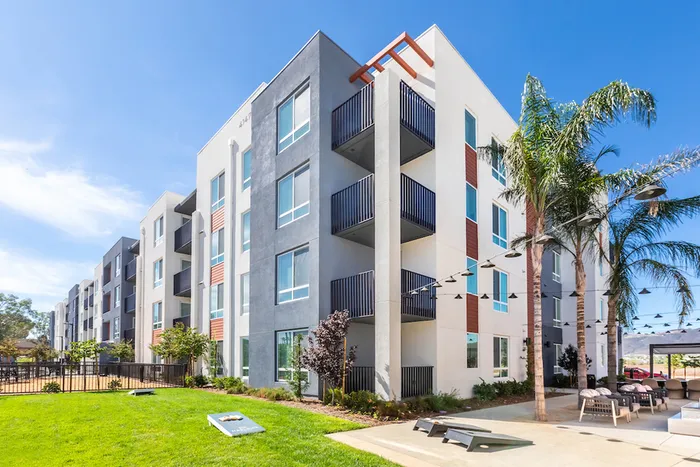 Modern apartment community featuring contemporary design, lush landscaping, and inviting outdoor seating under string lights.