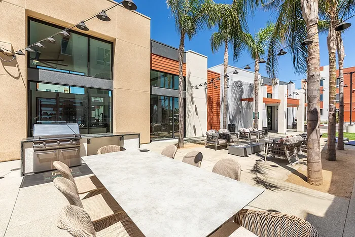 Luxurious outdoor patio featuring modern seating, sleek BBQ grill, and elegant palm trees, perfect for entertaining in style.